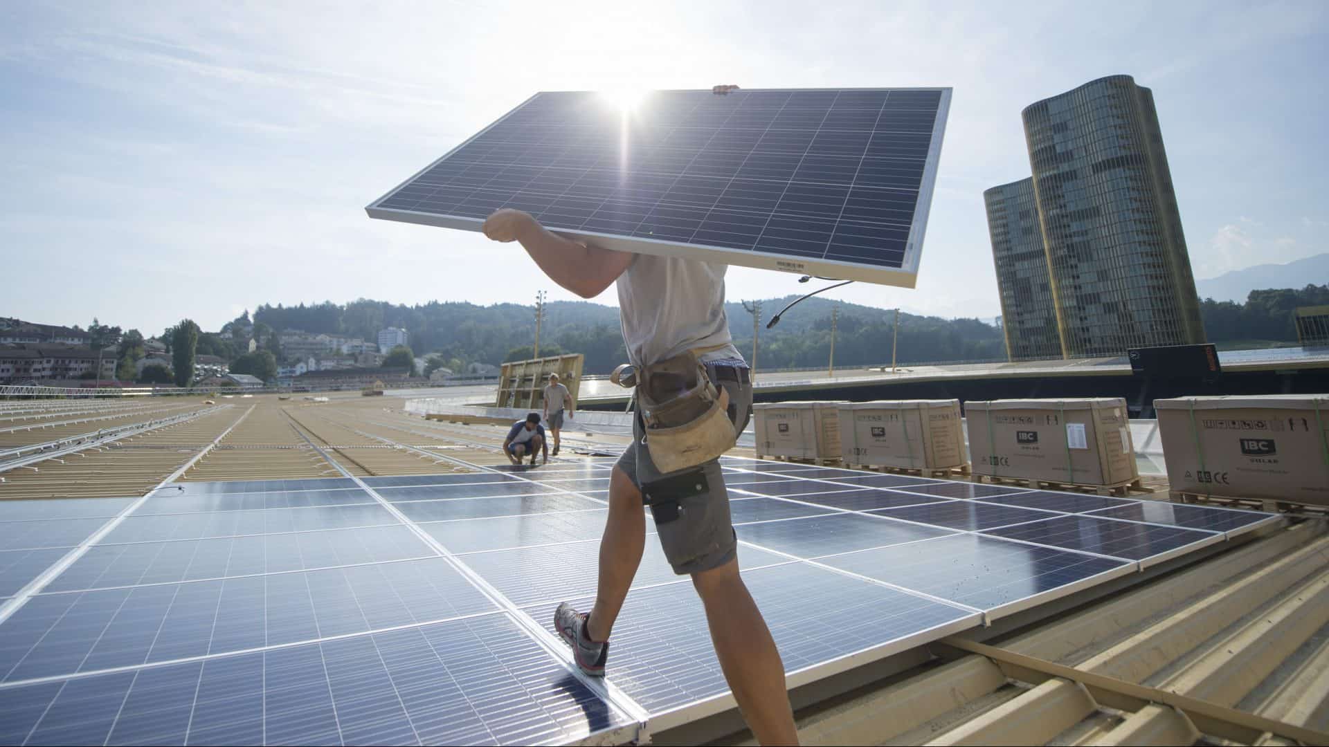 Un operaio edile trasporta un pannello solare sul tetto